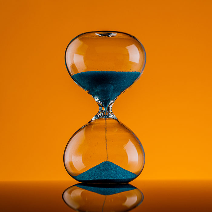An hourglass with sand falling indicating time passing.