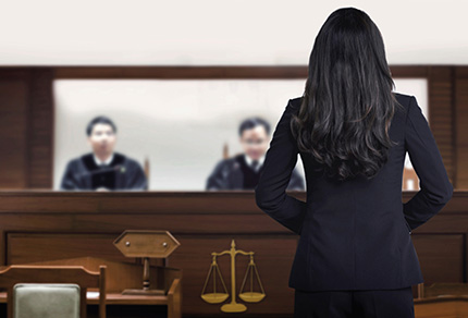 Female attorney standing and speaking in a courtroom.