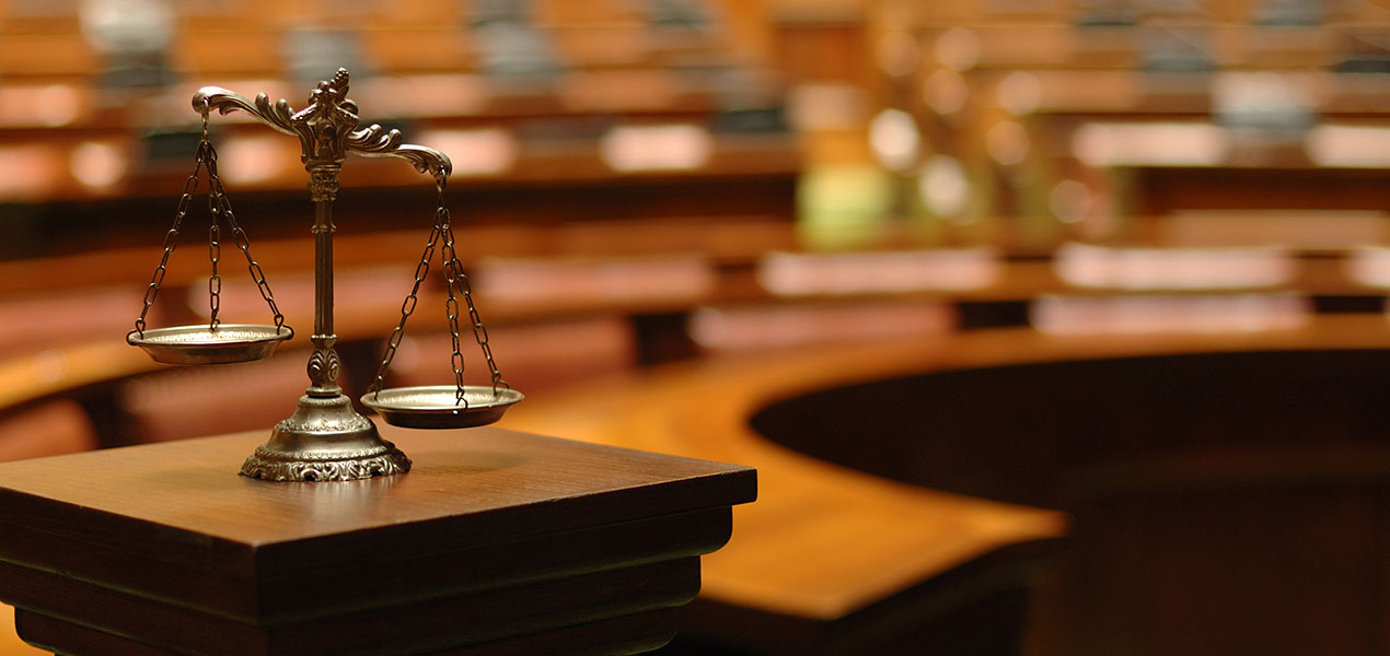 The scales of justice sitting on a wood railing in a courtroom