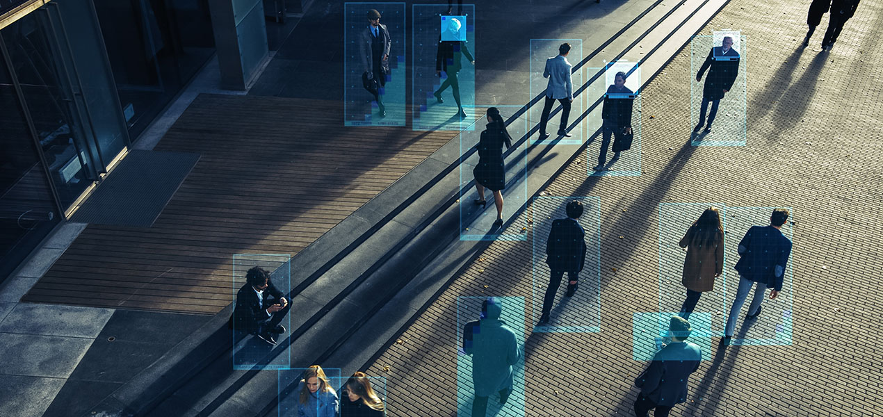 Security camera footage of a crowd of people walking on busy city street, with digital boxes outlining individual people.