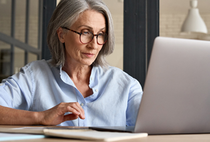 A mature woman working on a laptop.