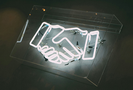 A neon sign of shaking hands.