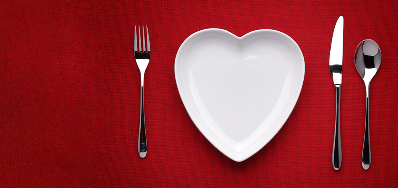 A heart shaped plate and place setting on a table.