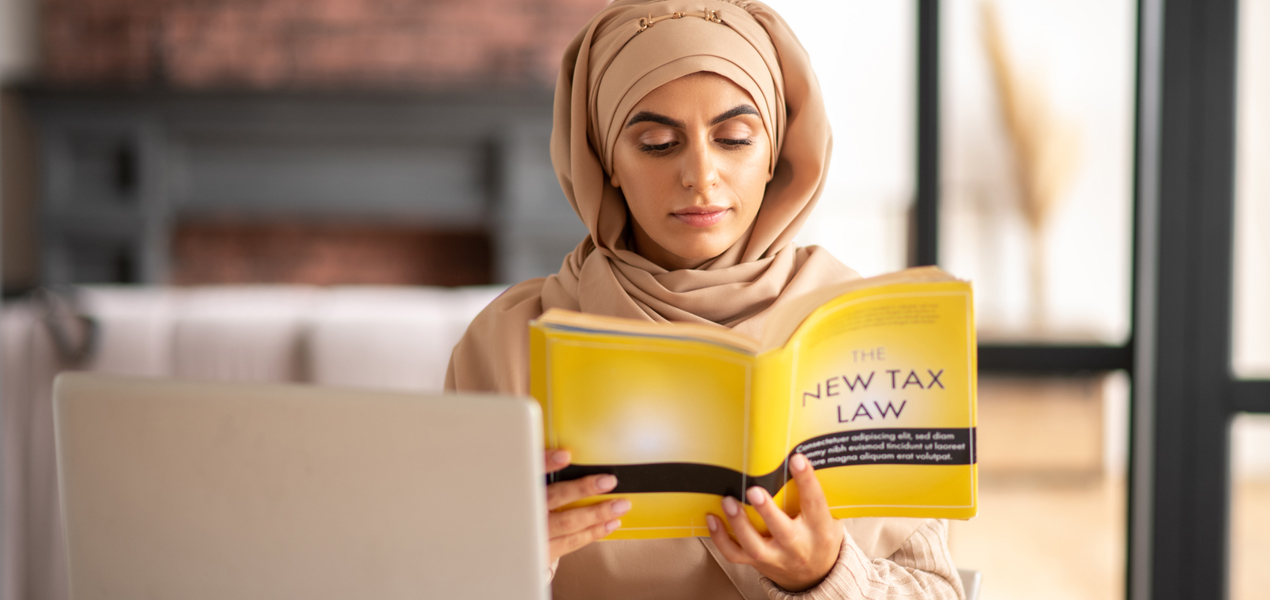 Muslim female reading a book about tax law.