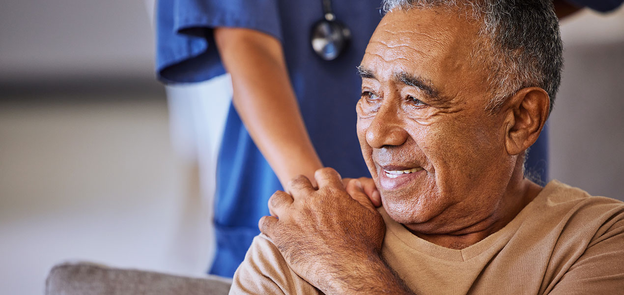 A medical professional holds the hand of a sad senior patient.