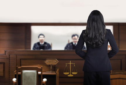 Female attorney standing and speaking in a courtroom.
