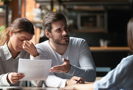 A young couple expressing frustration while meeting with their advisor.