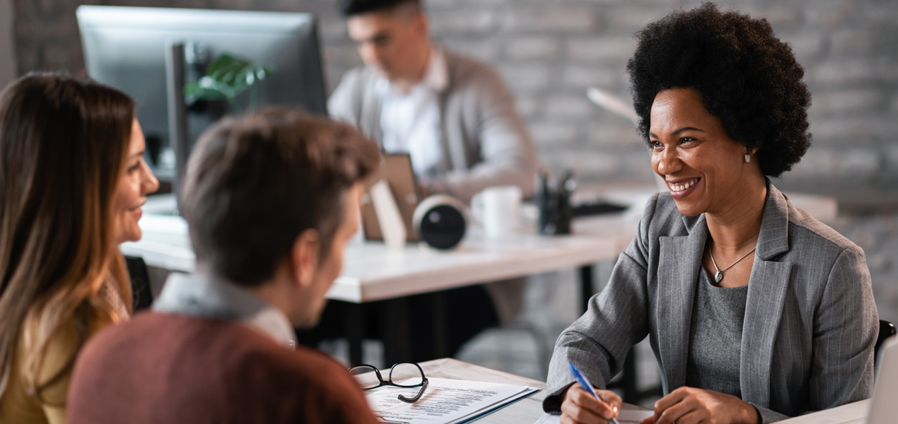 Smiling Black female business professional talking to a couple.