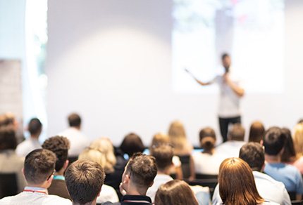 A speaker leading a session in front of a large group of people.