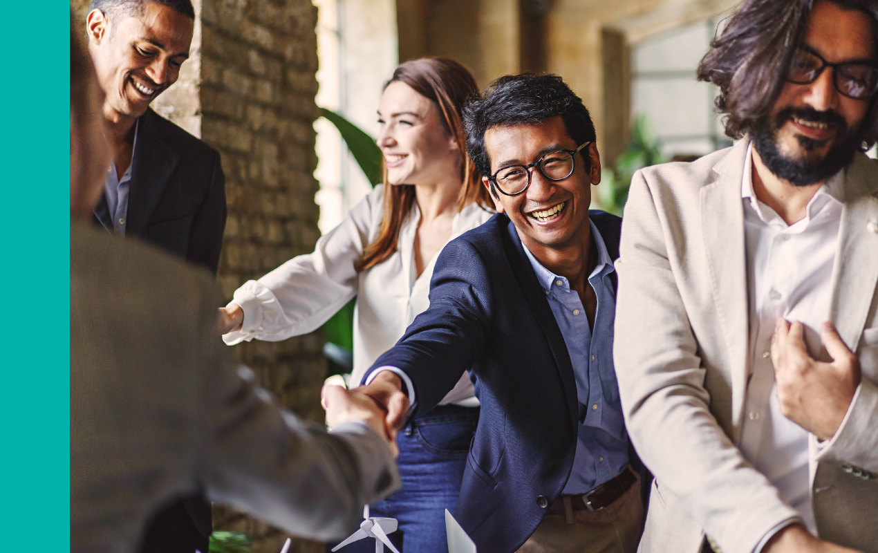 Group of diverse professionals celebrating with a handshake at a corporate event, embodying teamwork and achievement.