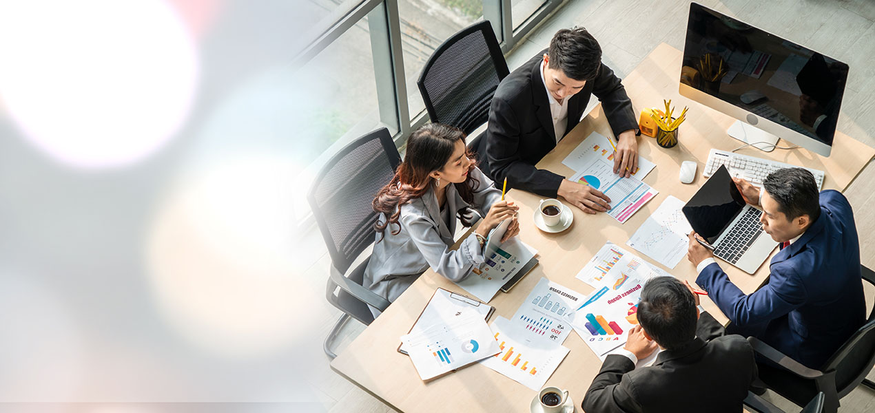 Group of four people at office meeting table, taken from above.