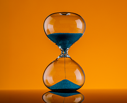 An hourglass sitting on a table with the sand falling.
