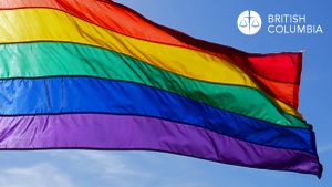 Pride flag blowing in the wind against a blue sky