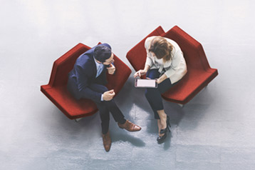 Aerial perspective of two people sitting on chairs having a serious conversation.