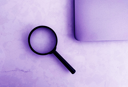 A magnifying glass and a laptop on a table.