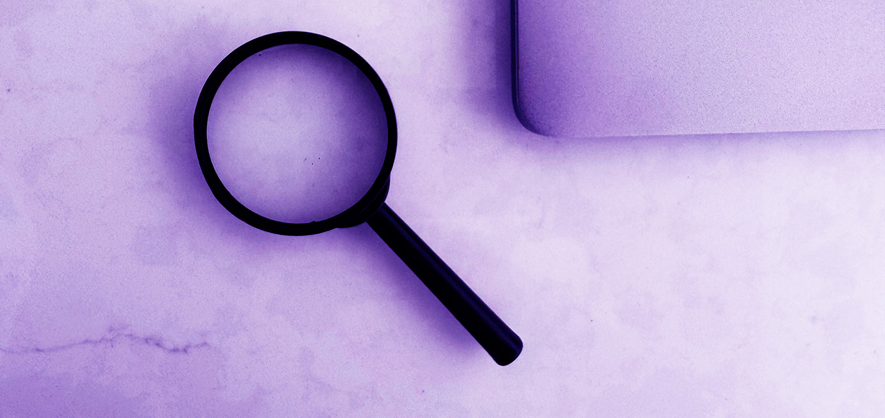 A magnifying glass and a laptop on a table.
