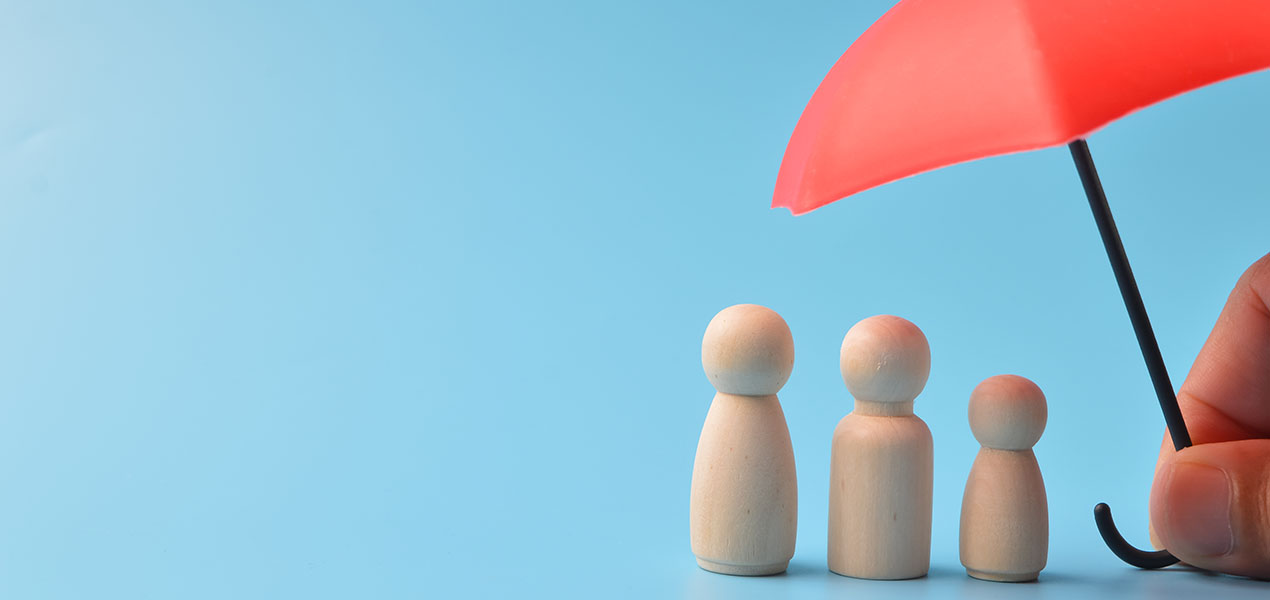 A red toy umbrella provides coverage for a set of wooden doll figures.
