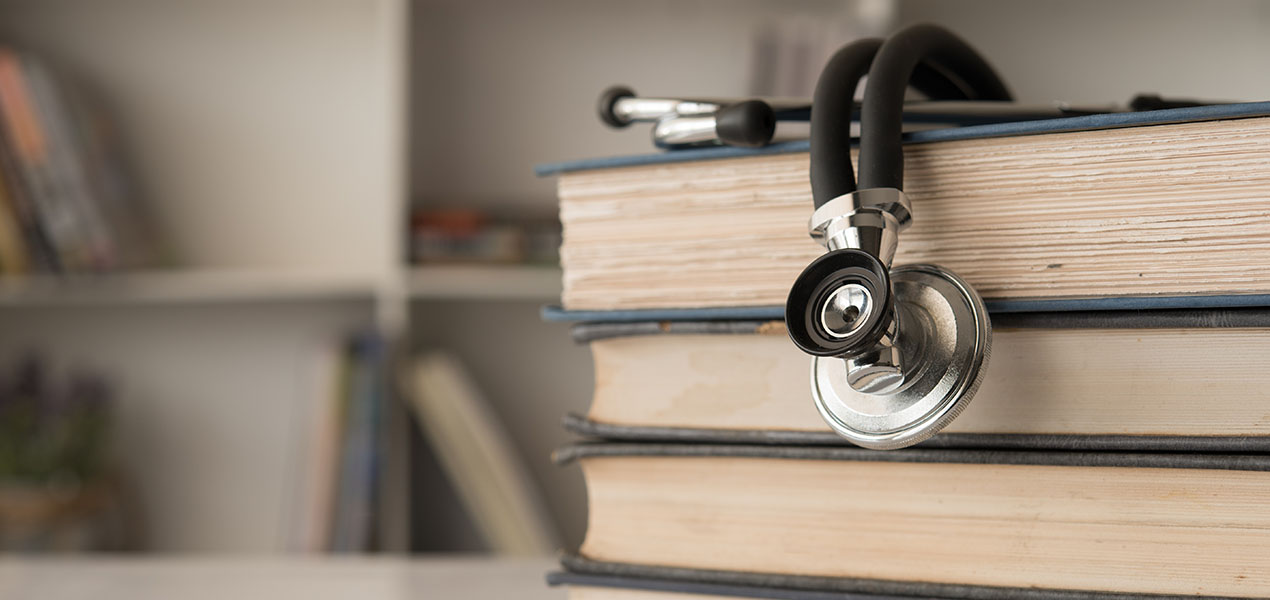 A stethoscope on a stack of medical books.