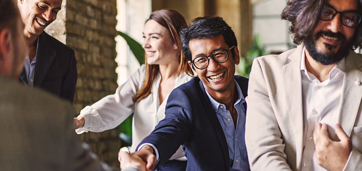 Group of diverse professionals celebrating with a handshake at a corporate event, embodying teamwork and achievement.