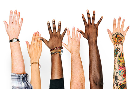 Hands and arms from a diverse group of individual help up high.
