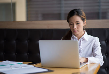 A young Asian business woman at coffee shop on her laptop.