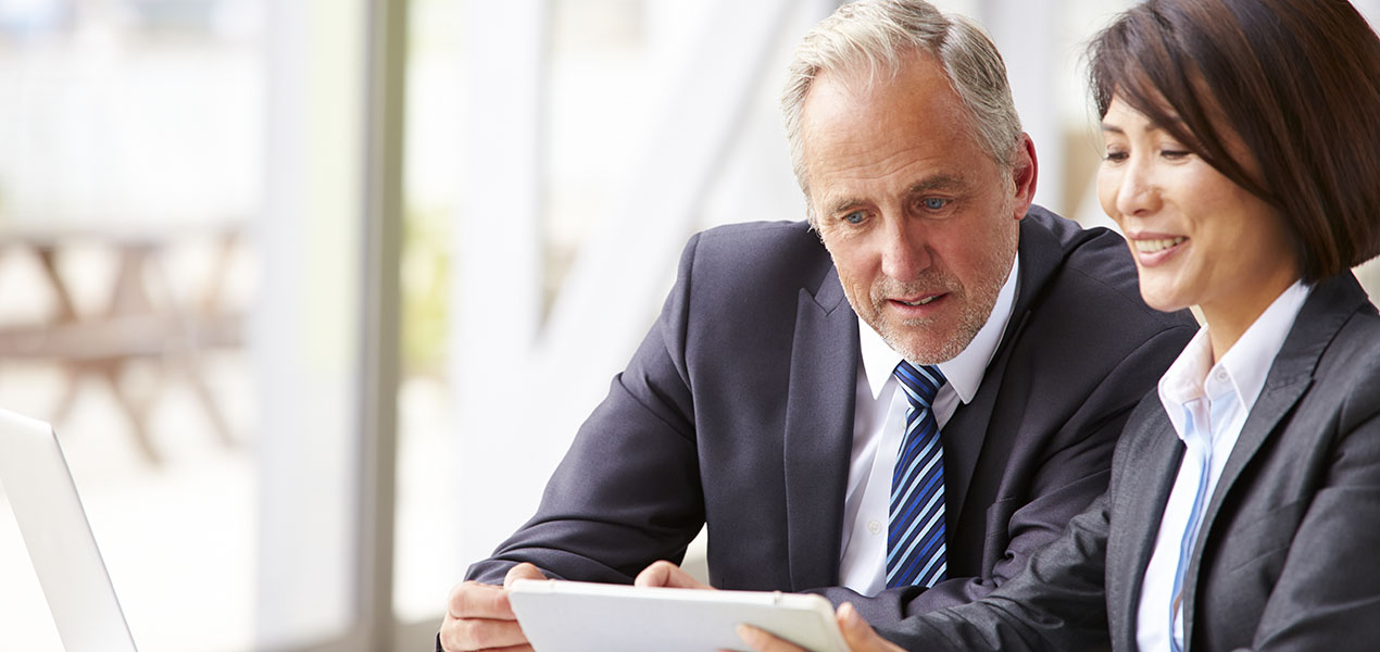 Two mature business professionals looking at a tablet.