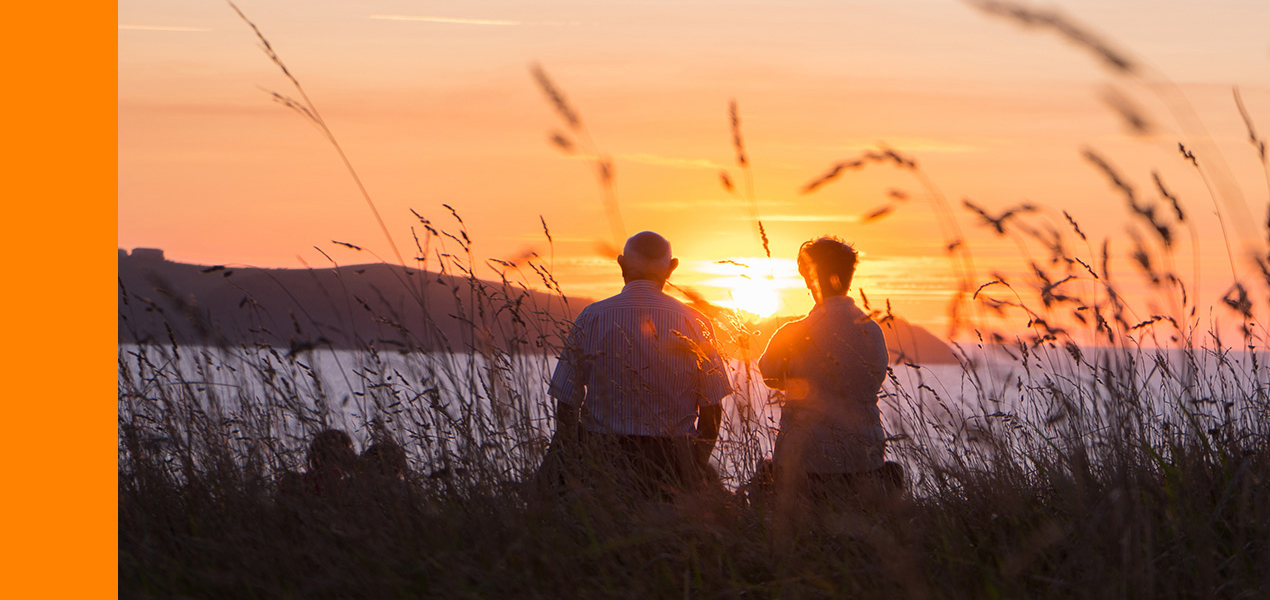 An elderly couple watching the sunset. 