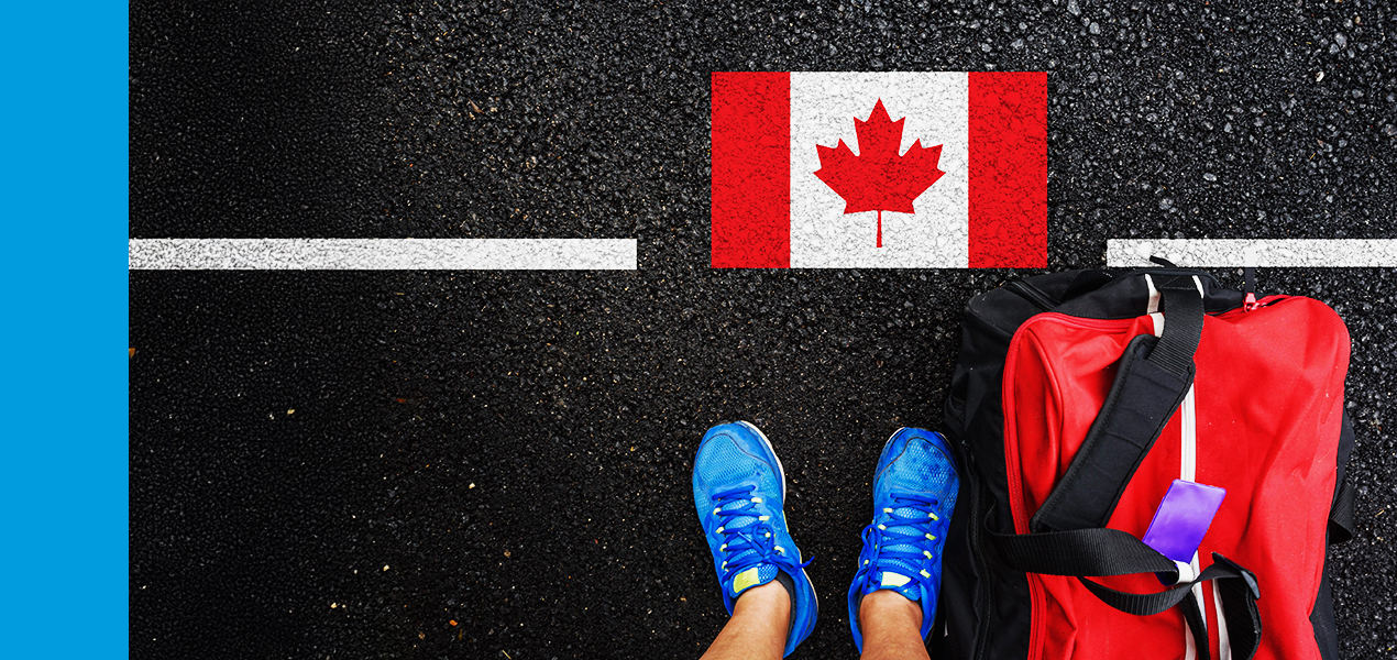 An aerial view of a person standing on pavement with a Canadian flag at their feet.