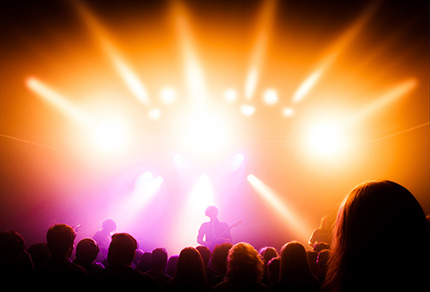 A band playing with bright lights illuminating the stage and the crowd. 