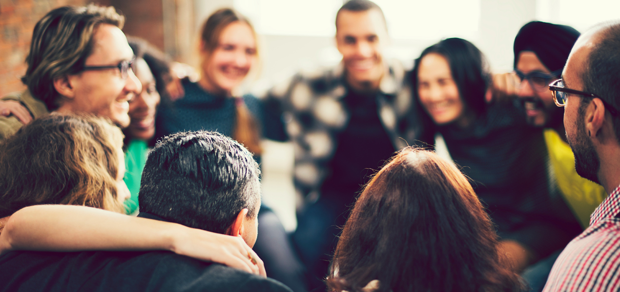 A team in a group huddle holding onto each other's shoulders.