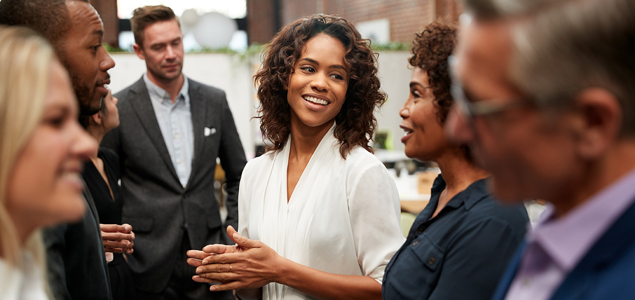 A businesswoman smiling while networking with a diverse group of people.