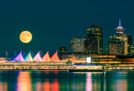 The Vancouver Convention Centre at night with a full moon in the sky.