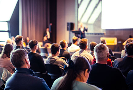 A wide view of conference attendees listening to a presentation.